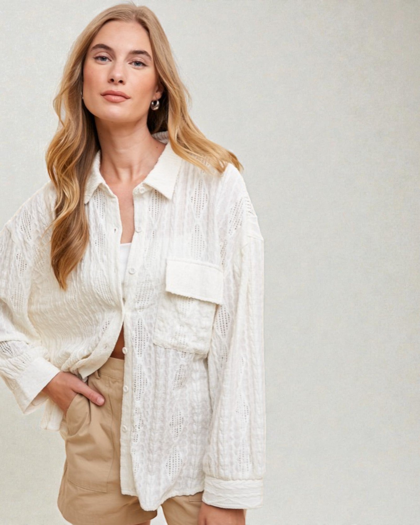 Woman wearing a white textured shirt and beige pants against a plain background