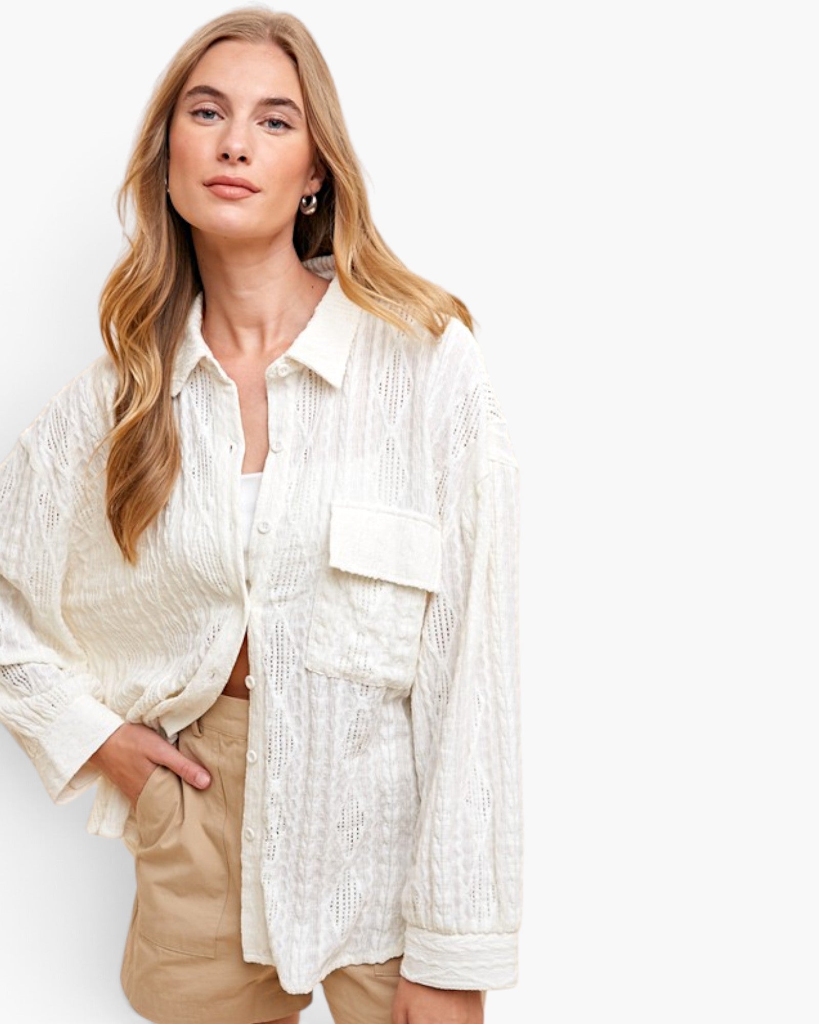 A woman wearing a textured off-white button-up shirt with a chest pocket and beige shorts, posed against a clean white background.