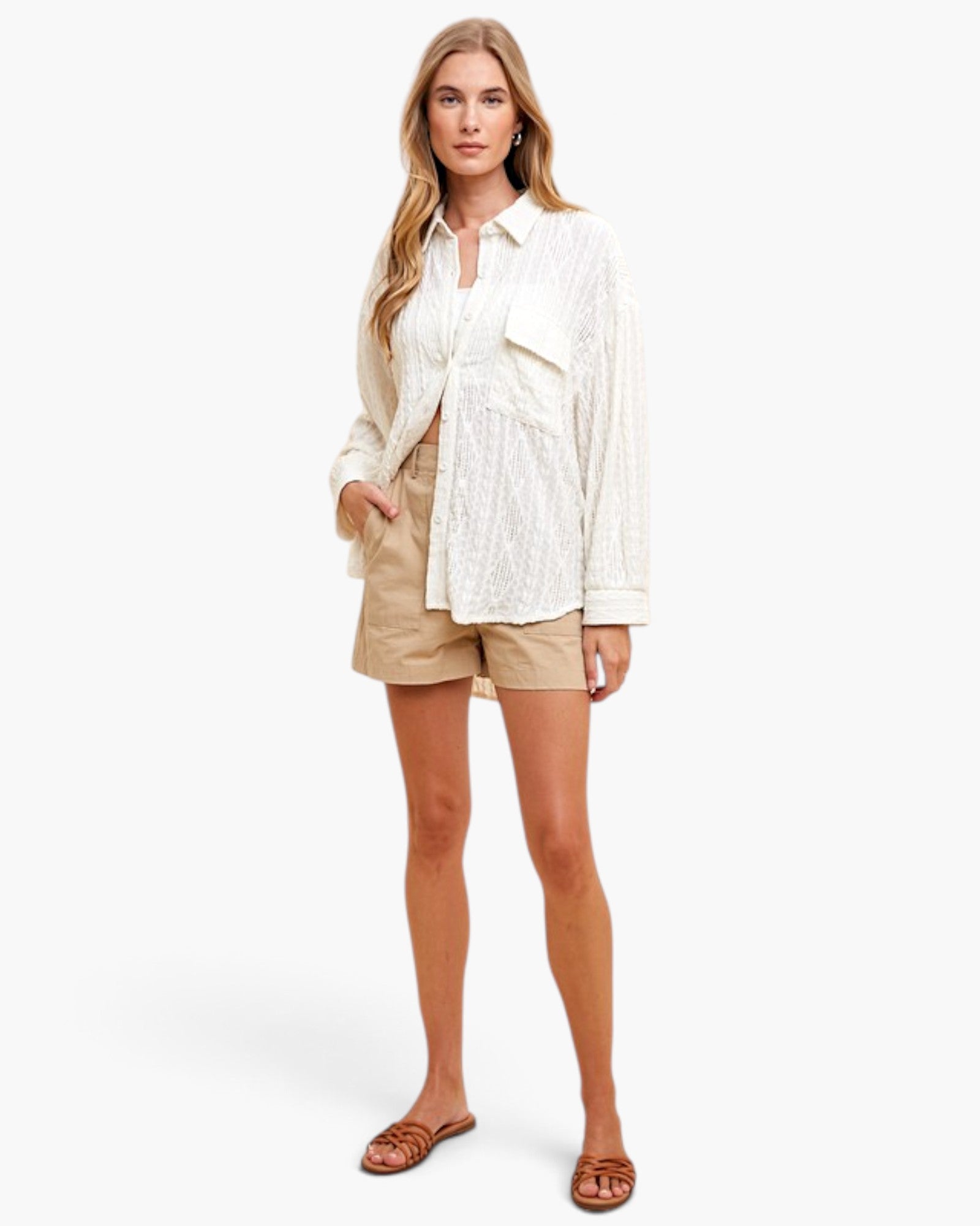 A woman modeling a white textured button-up shirt and beige shorts against a clean white studio background.
