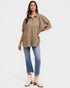 Woman wearing a striped shirt and jeans with white boots on a white background