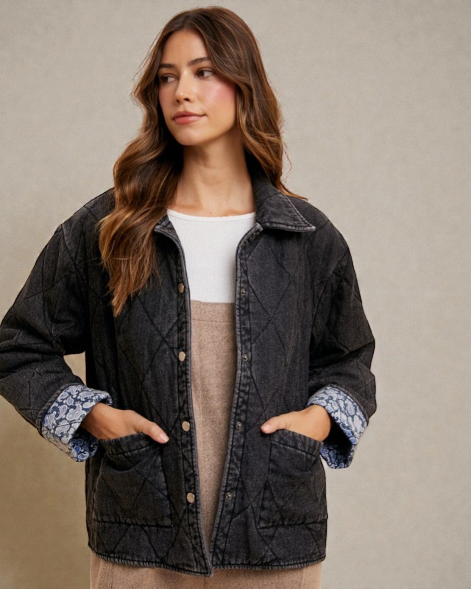 Woman wearing a dark quilted jacket with floral cuffs against a beige background