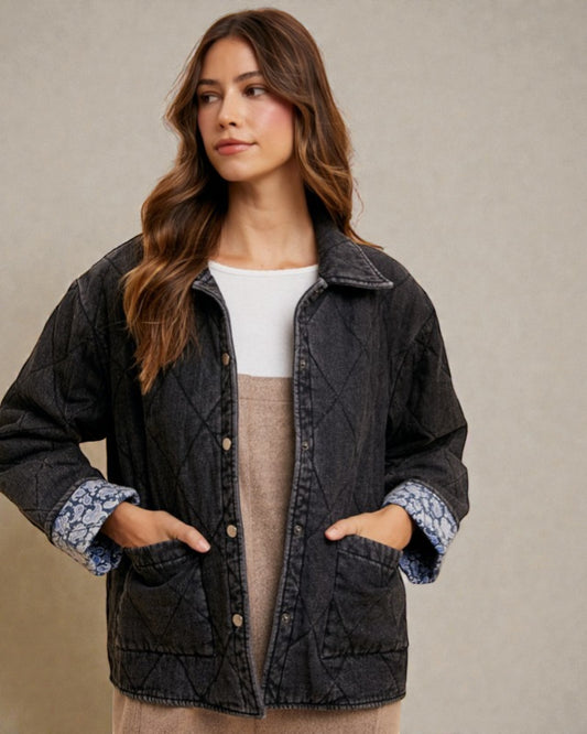 Woman wearing a dark quilted jacket with floral cuffs against a beige background