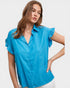 Woman wearing a blue blouse with ruffled sleeves on a plain background