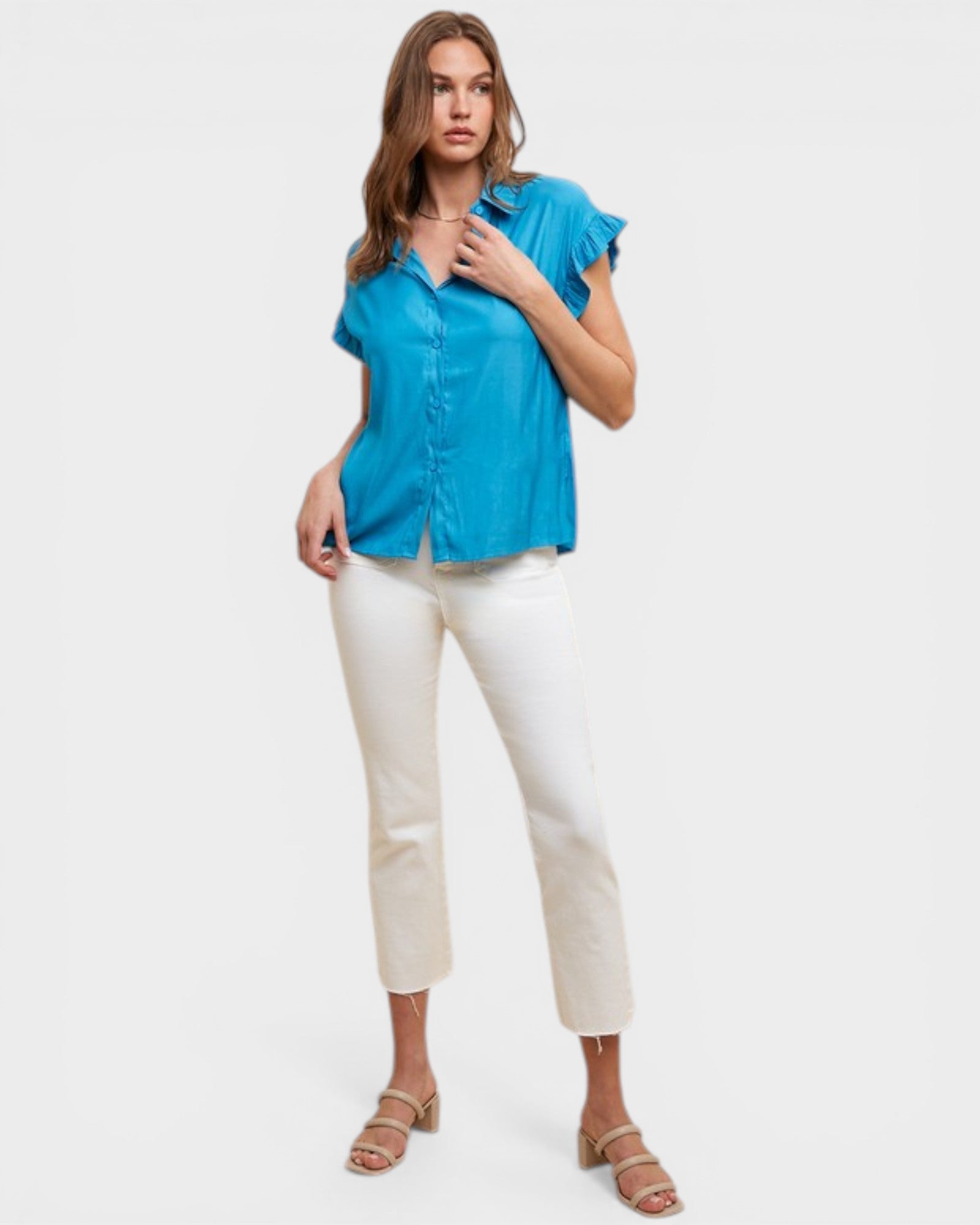 Woman wearing a blue shirt and white pants on a light gray background