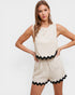 Woman wearing a beige romper with black trim on a white background