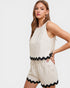 Woman wearing a beige romper with black trim on a white background