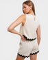 Woman wearing a white romper with black trim on a plain background