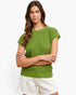 A woman modeling a bright green short-sleeve ribbed knit top with white shorts against a plain white studio background.