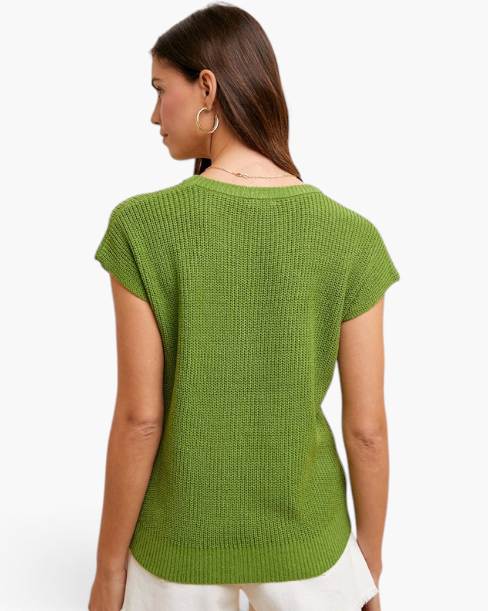 A woman shown from the back wearing a textured lime green short-sleeve knit top and white pants against a plain white background.