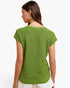 A woman shown from the back wearing a textured lime green short-sleeve knit top and white pants against a plain white background.