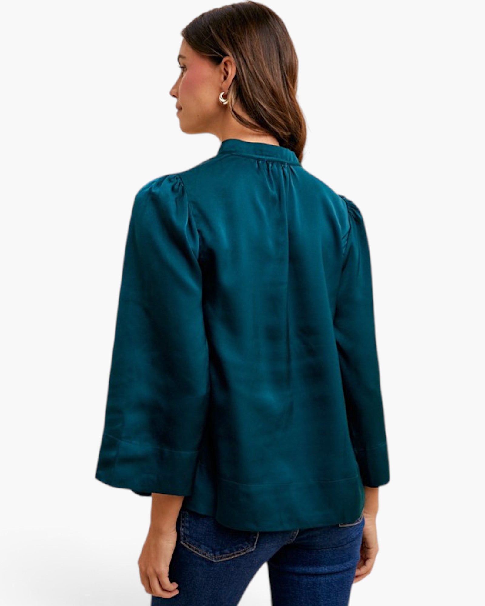A woman shown from the back wearing a dark teal green satin blouse with three-quarter sleeves and blue jeans, set against a plain white studio background.