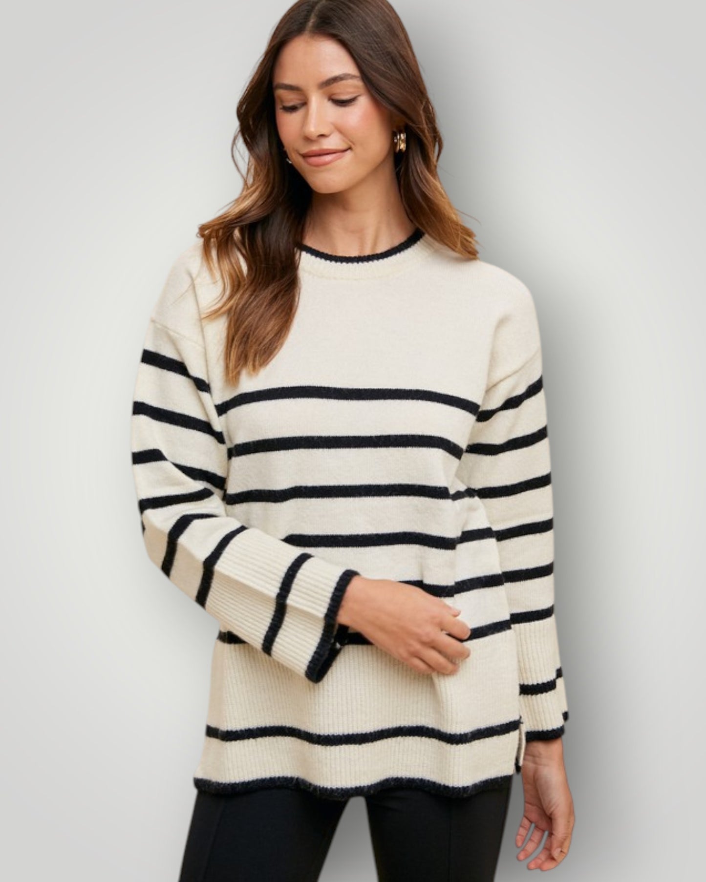 Woman wearing a cream and navy striped sweater against a plain background