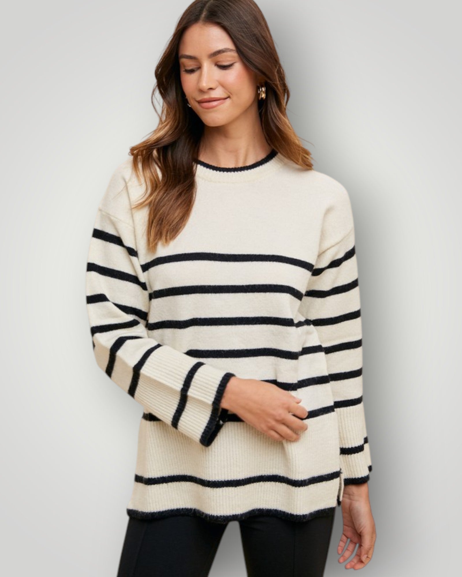 Woman wearing a cream and navy striped sweater against a plain background