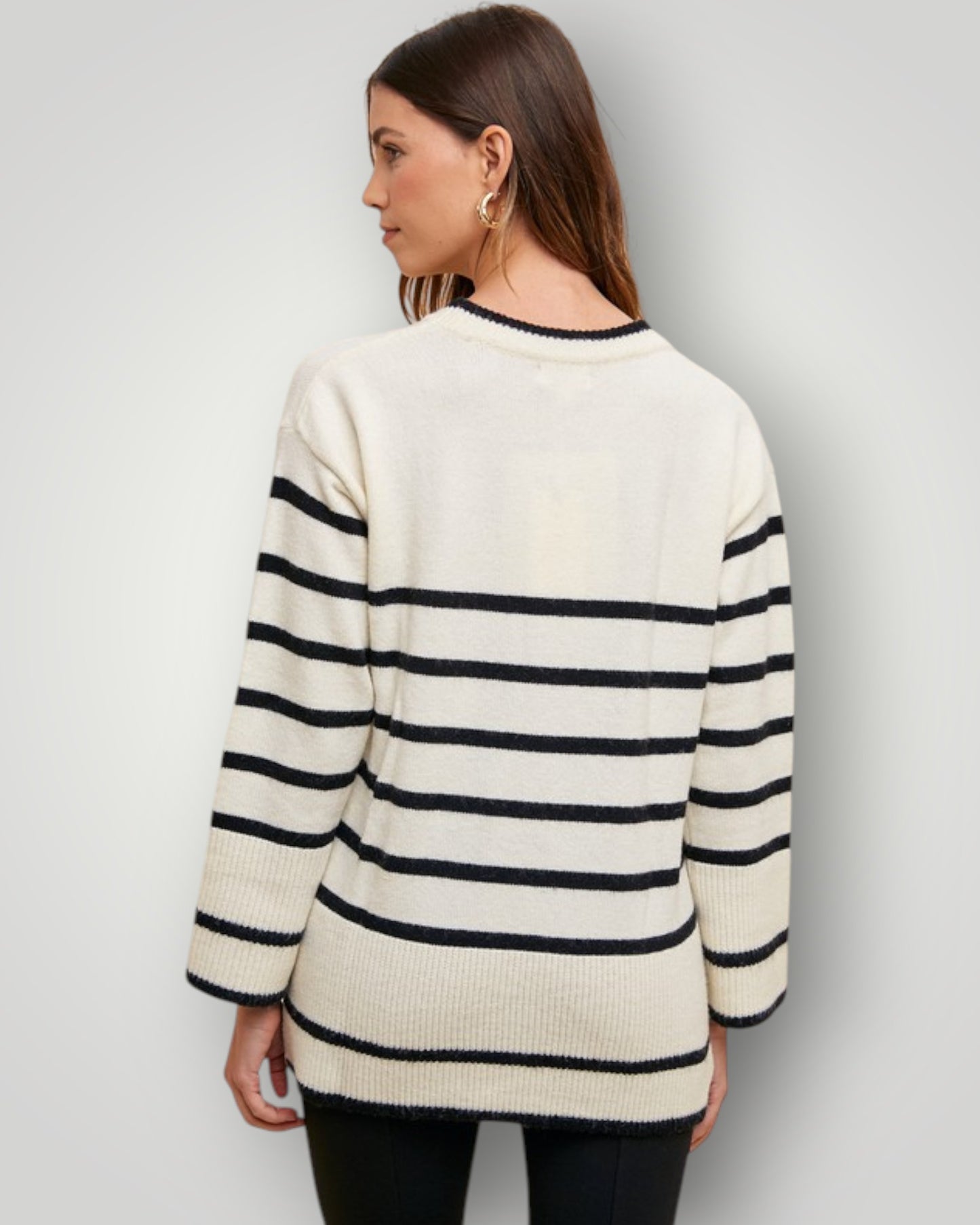 Woman wearing a cream and navy striped sweater against a plain background