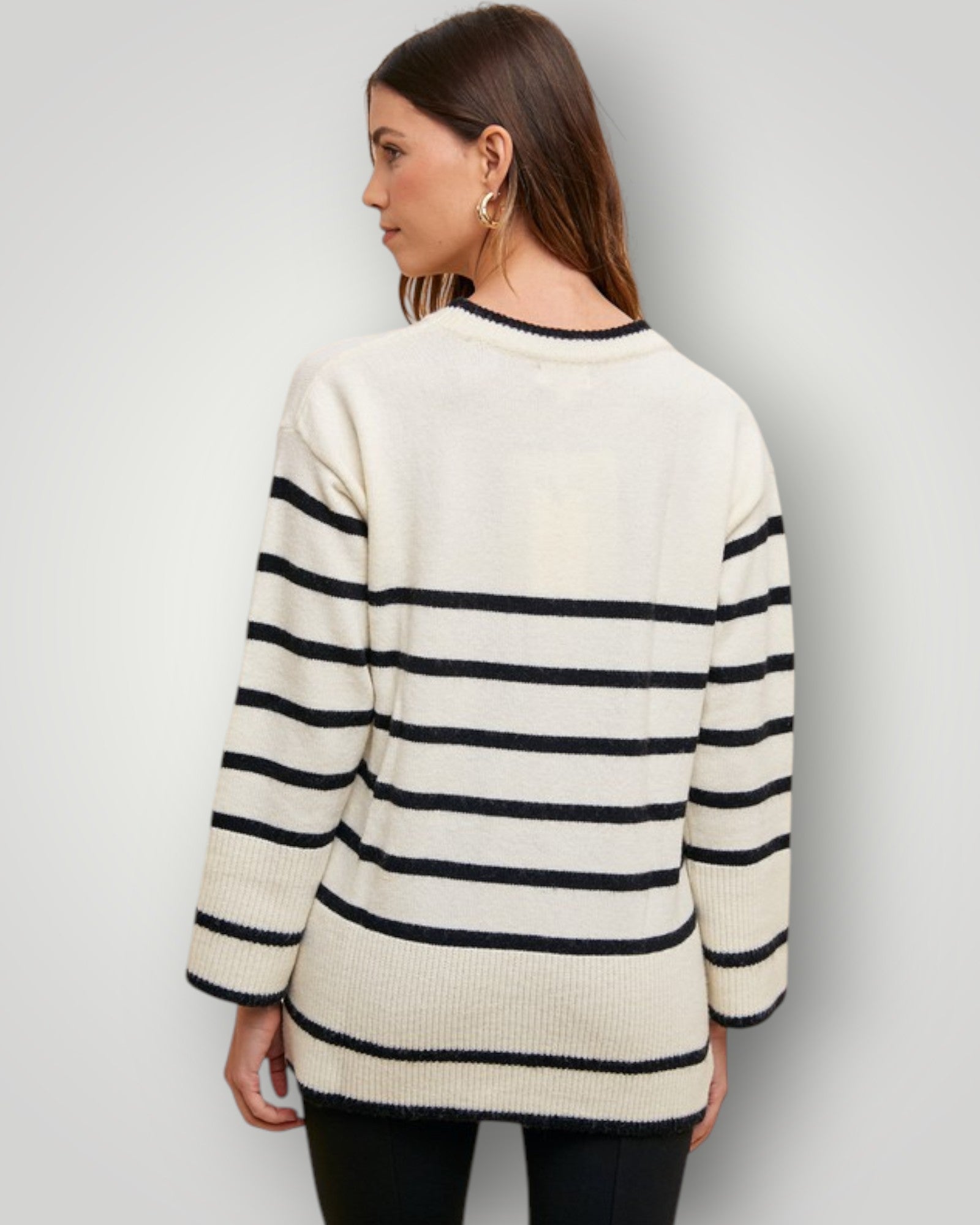 Woman wearing a cream and navy striped sweater against a plain background