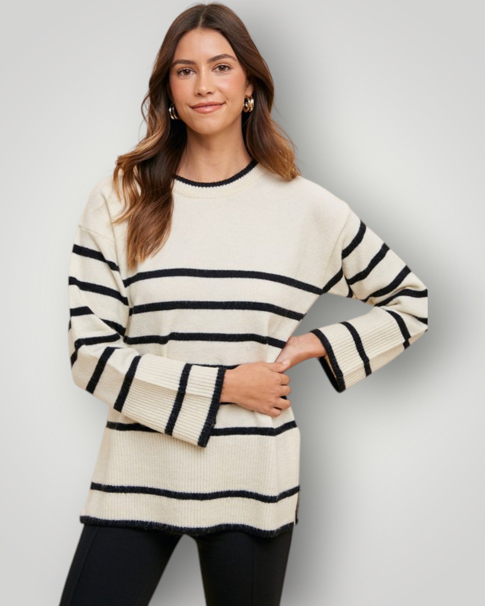 Woman wearing a cream and black striped sweater on a plain background