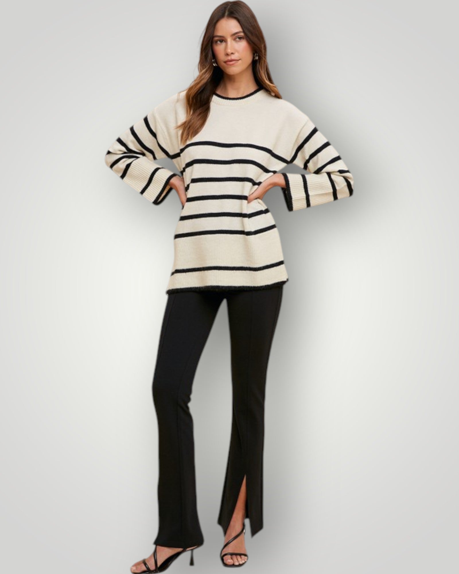 Woman wearing a black and white striped sweater with black pants on a light gray background
