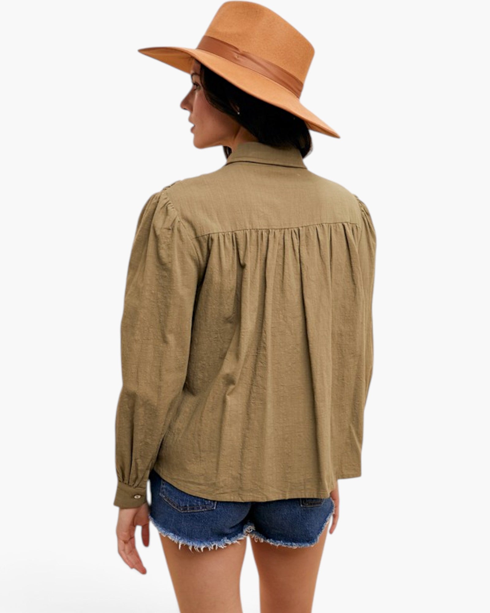 A woman shown from the back wearing a light brown long-sleeve blouse with gathered detailing at the shoulders and waist, paired with denim shorts and a tan wide-brim hat, against a plain white background.