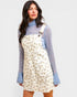 Woman wearing a floral dress over a patterned sweater on a light gray background