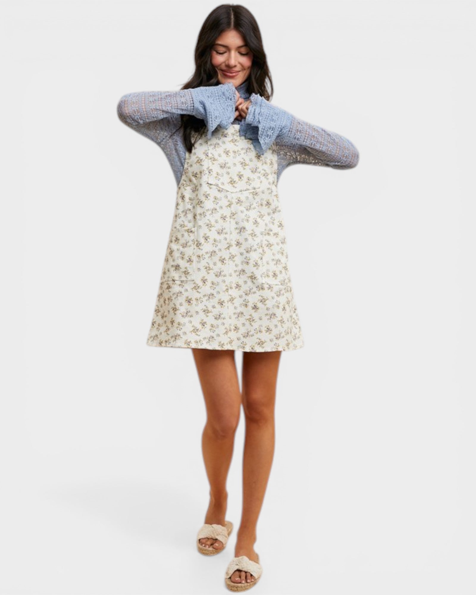 Woman wearing a floral dress and denim jacket on a white background