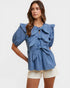 Woman wearing a blue ruffled blouse with a white background