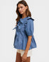 Woman wearing a blue striped blouse with ruffled details on a white background