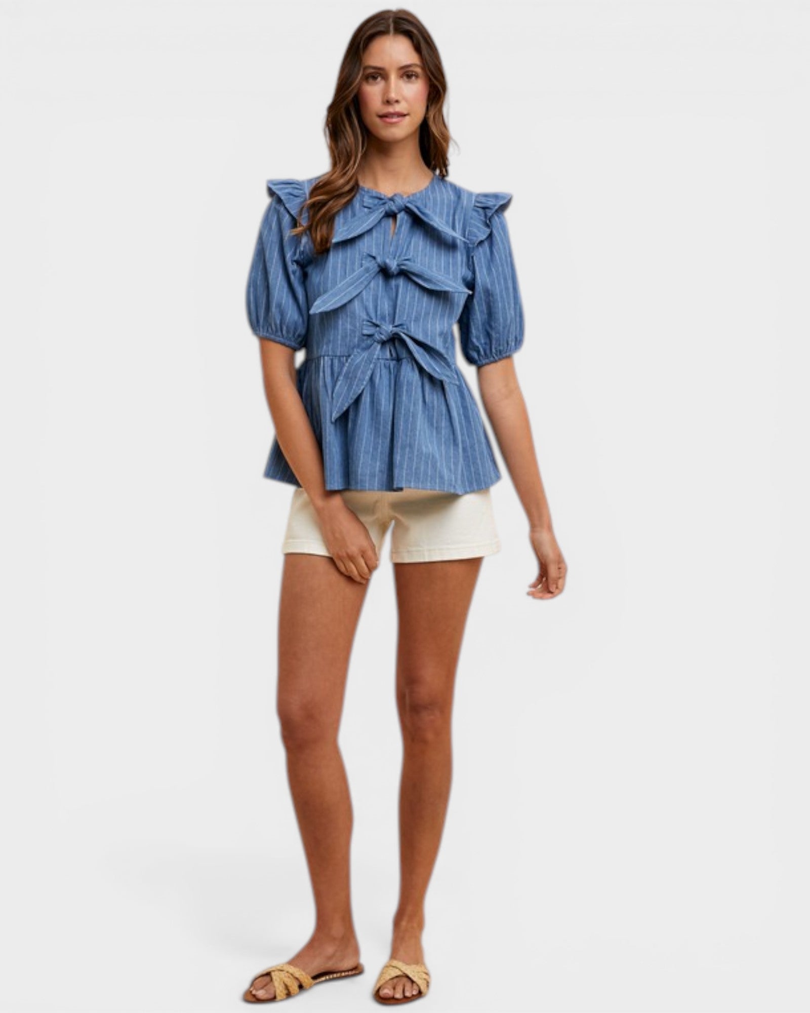 Woman wearing a blue ruffled top and white shorts on a white background