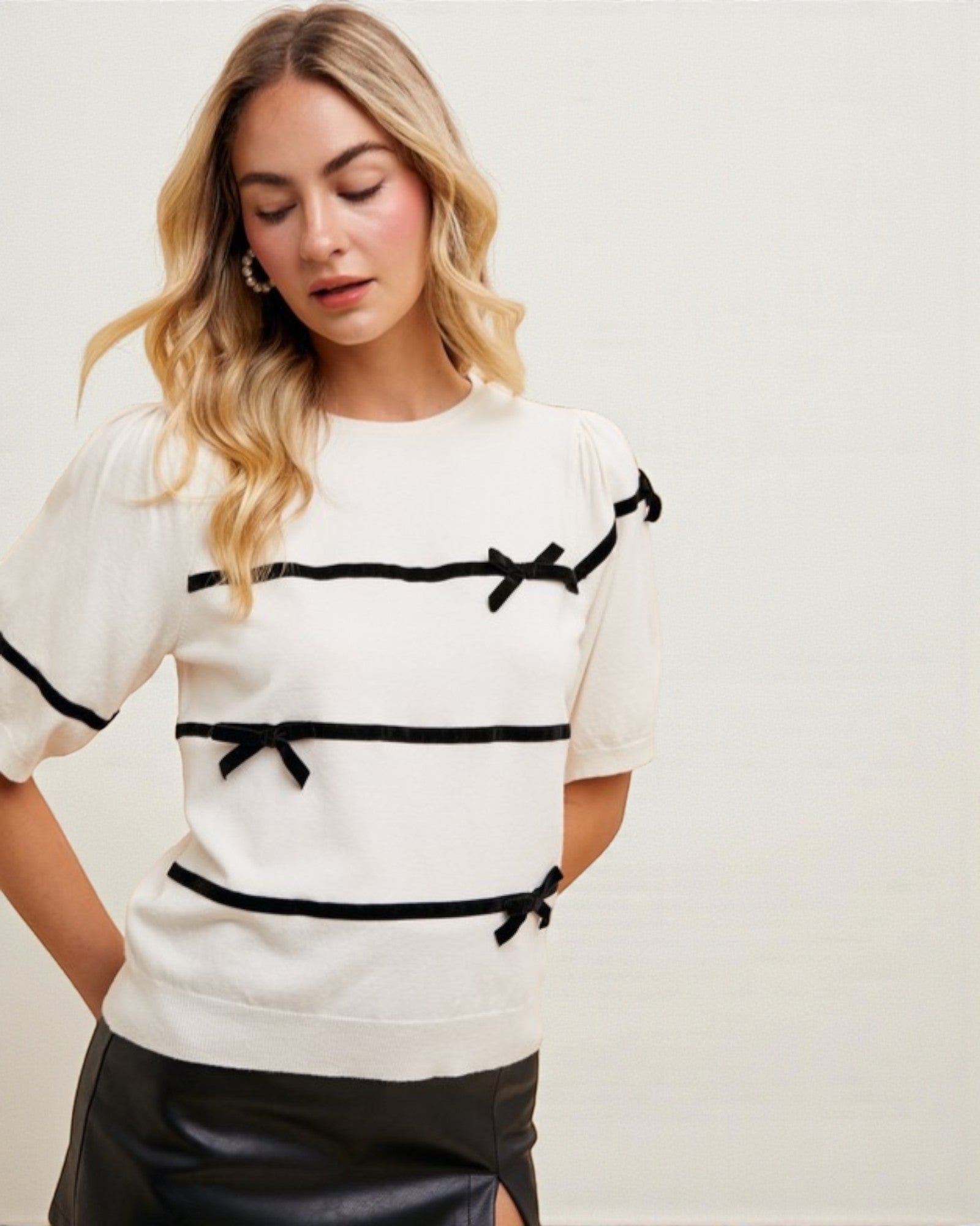 Woman wearing a white top with black accents on a plain background