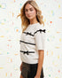 Woman wearing a white sweater with black ribbons against a colorful abstract background