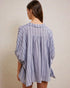 Woman wearing a blue and white striped shirt against a beige background