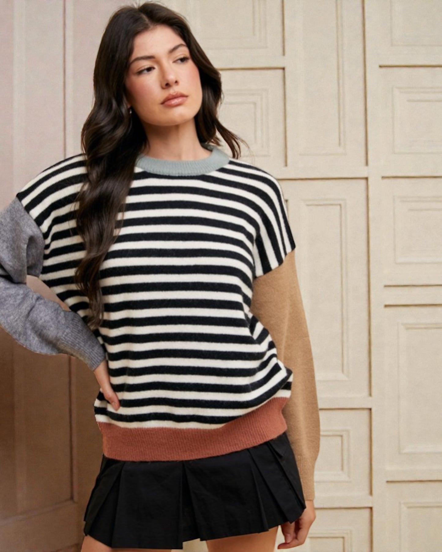 Woman wearing a black and white striped sweater with a beige background