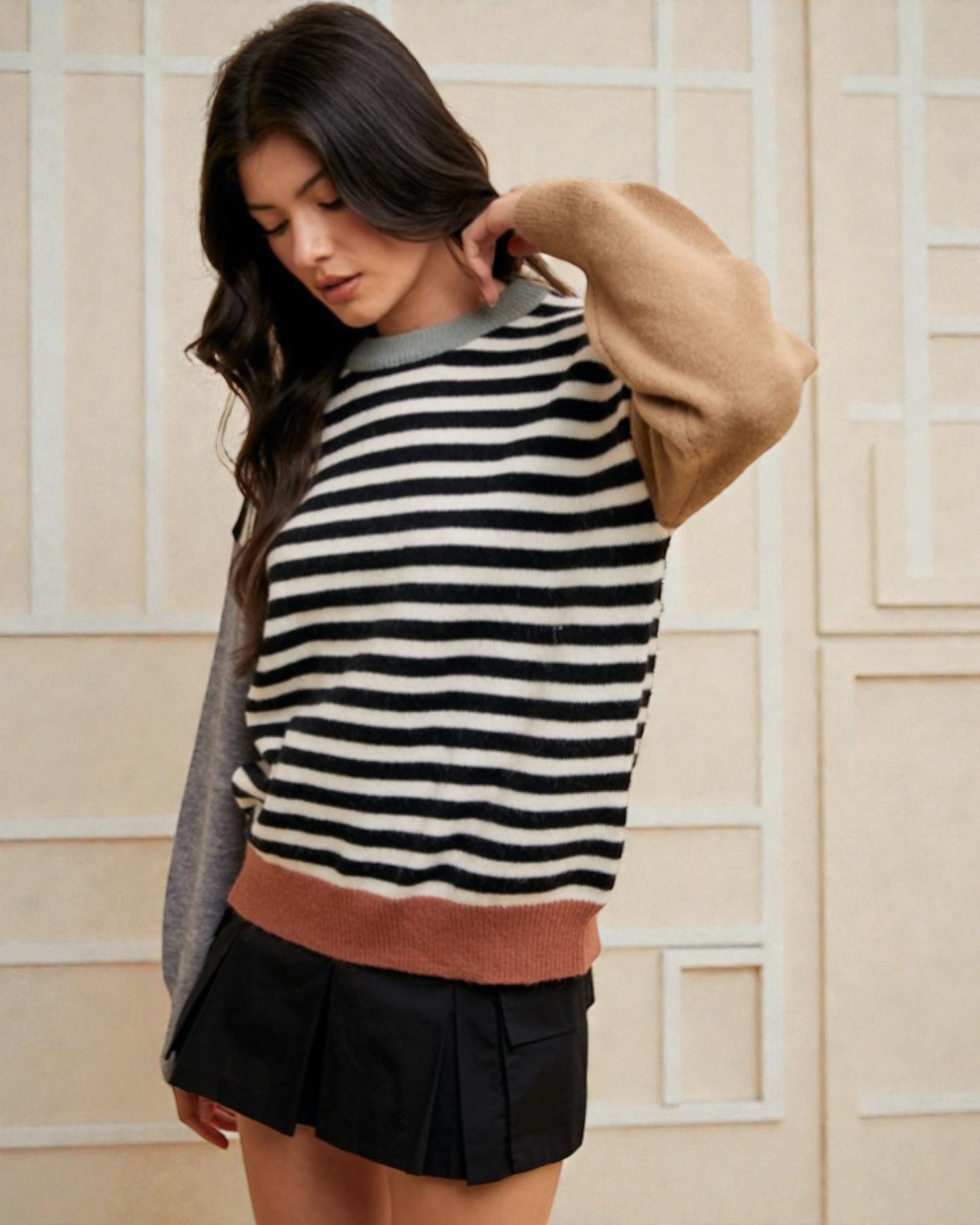 Woman wearing a striped sweater with a beige and brown color scheme against a neutral background