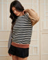 Woman wearing a striped sweater with a beige and brown color scheme against a neutral background
