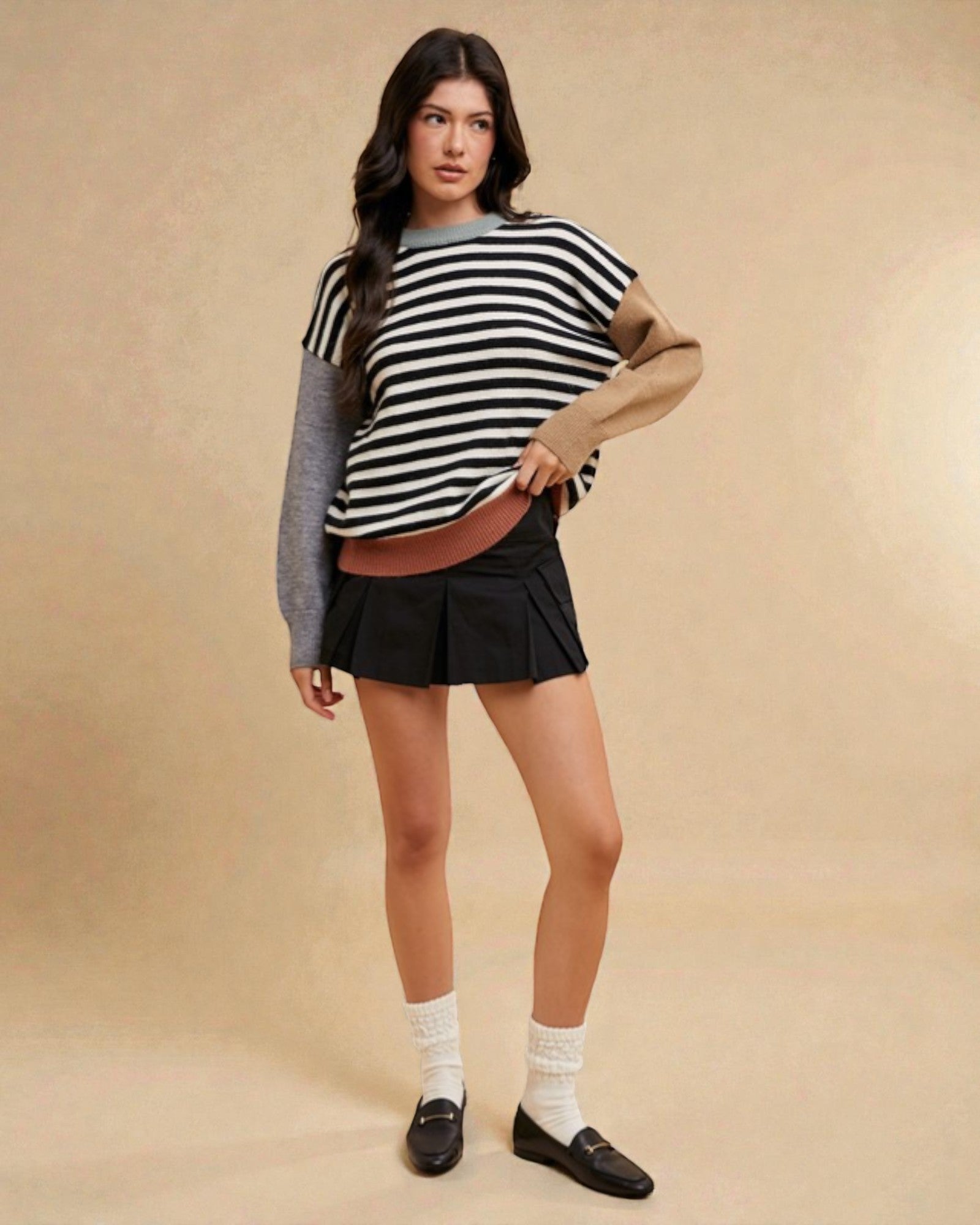Woman wearing a striped sweater and black skirt on a beige background