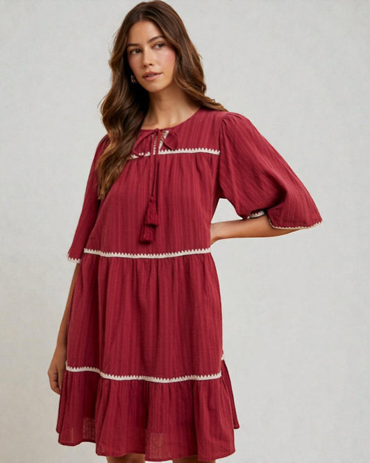 Woman wearing a red dress with white trim on a plain background