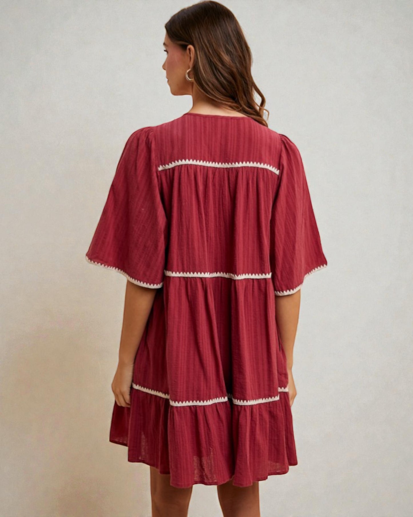 Red dress with white trim worn by a person on a plain background