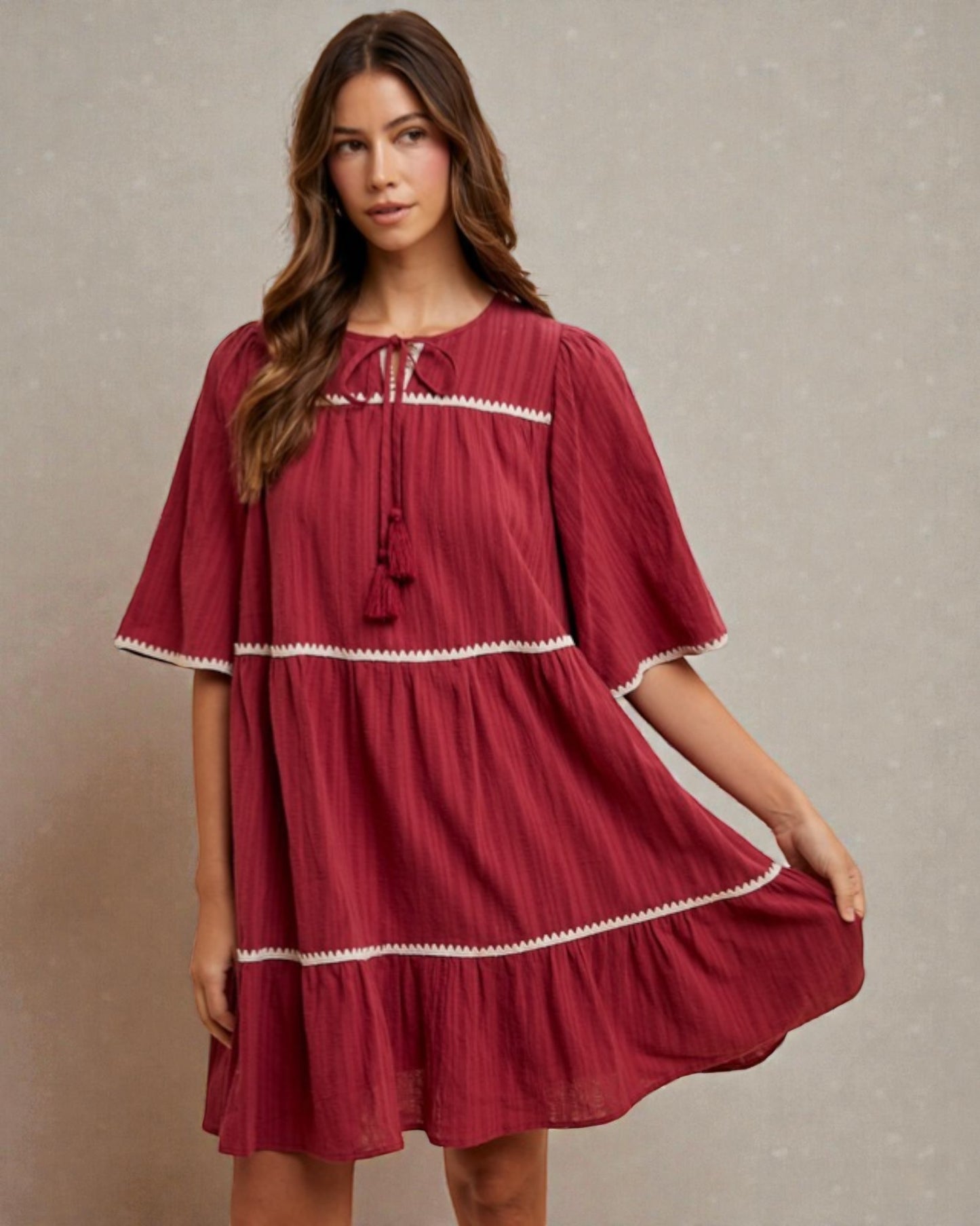 Woman wearing a red dress with white trim against a neutral background