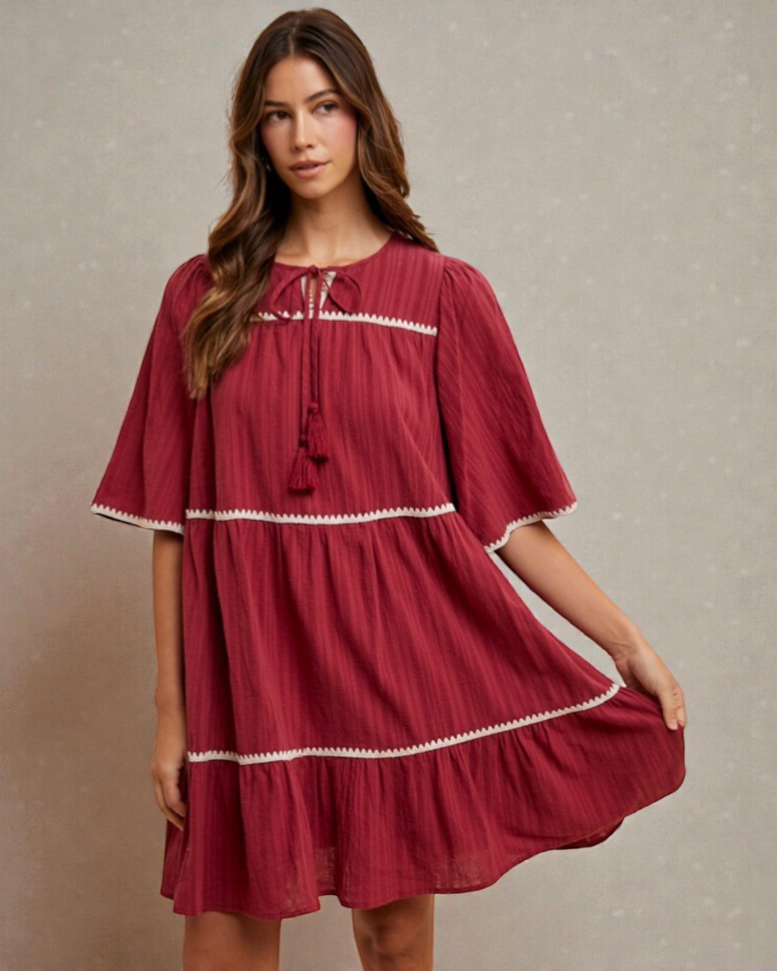 Woman wearing a red dress with white trim against a neutral background