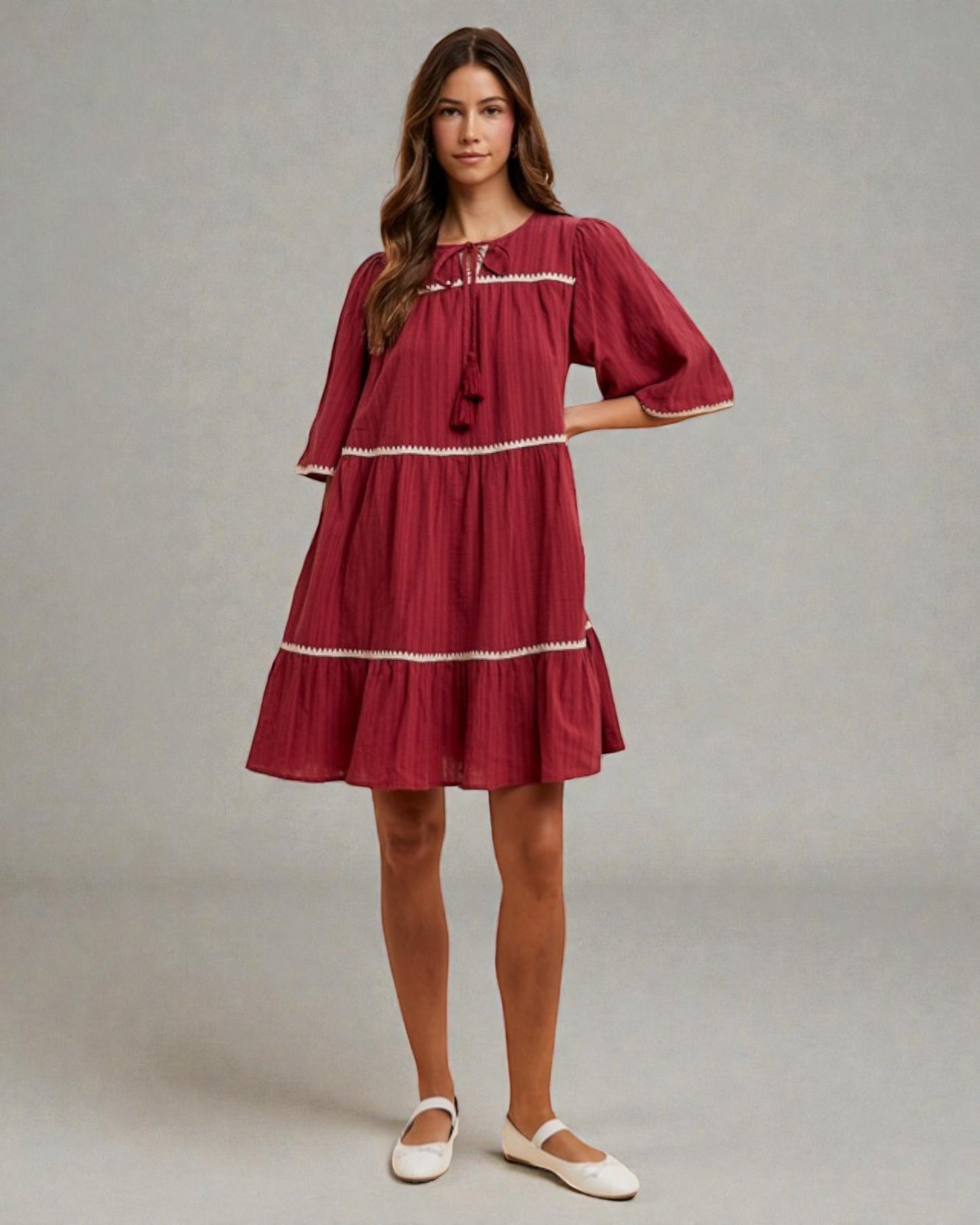 Woman wearing a red dress with white trim on a gray background