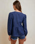 Woman wearing a blue denim blouse with puffed sleeves on a beige background