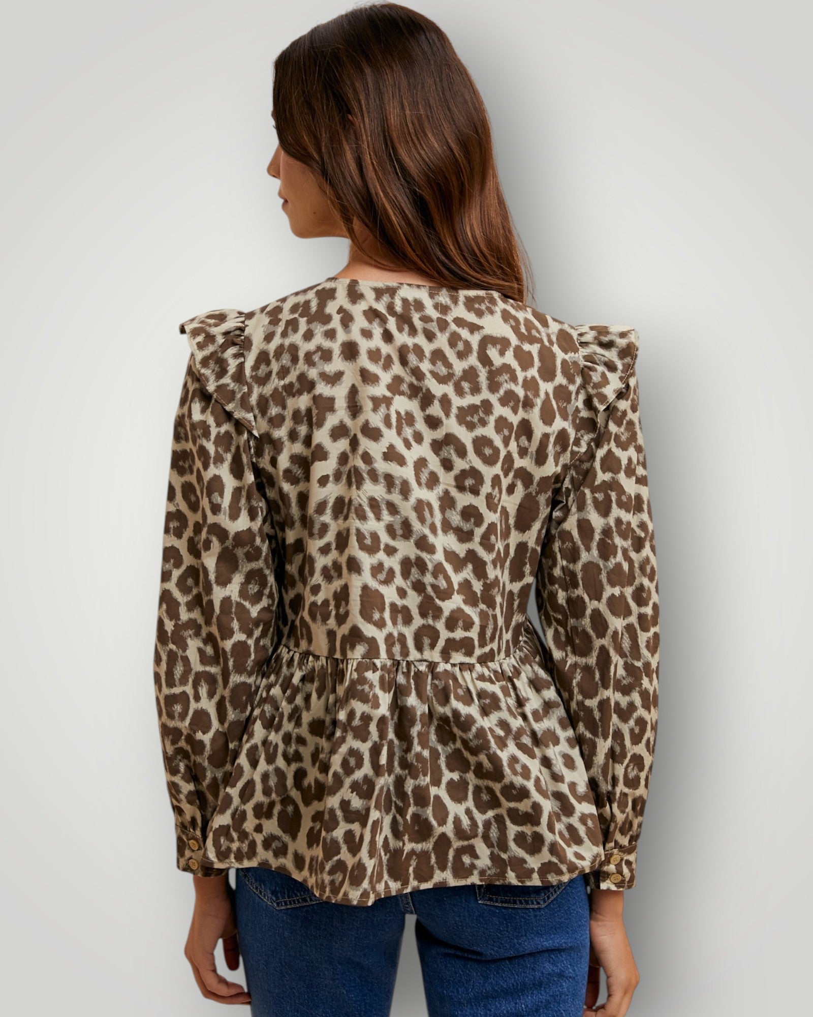 Woman wearing a leopard print blouse against a plain background