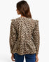A woman viewed from the back wearing a leopard-print long-sleeve blouse with ruffled shoulders and a peplum hem, paired with blue jeans, against a plain white studio background.