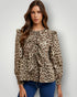 Woman wearing a leopard print blouse with ruffled details on a plain background