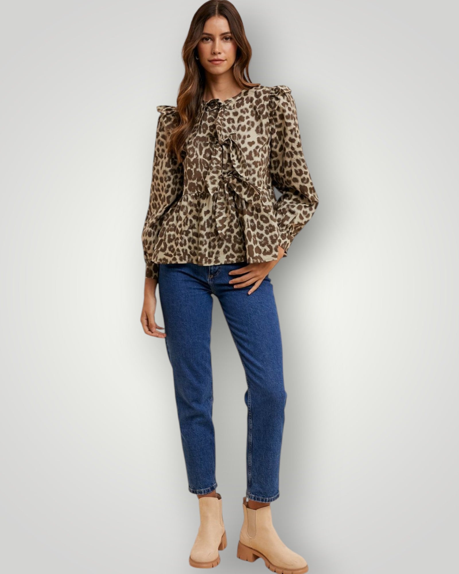 Woman wearing a leopard print top and blue jeans on a white background