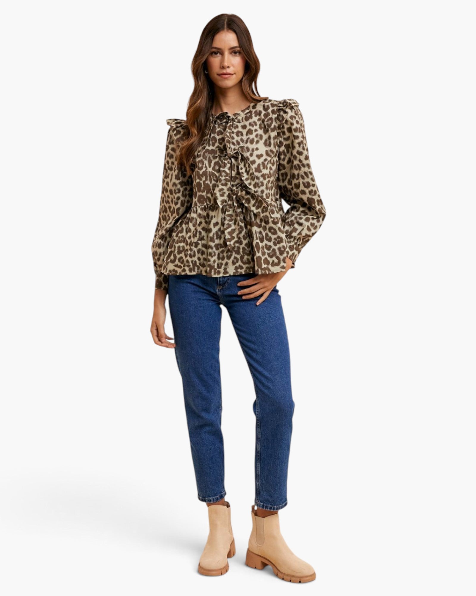 A woman modeling a leopard-print long-sleeve blouse with ruffled details, paired with blue jeans and beige ankle boots, against a plain white studio background.