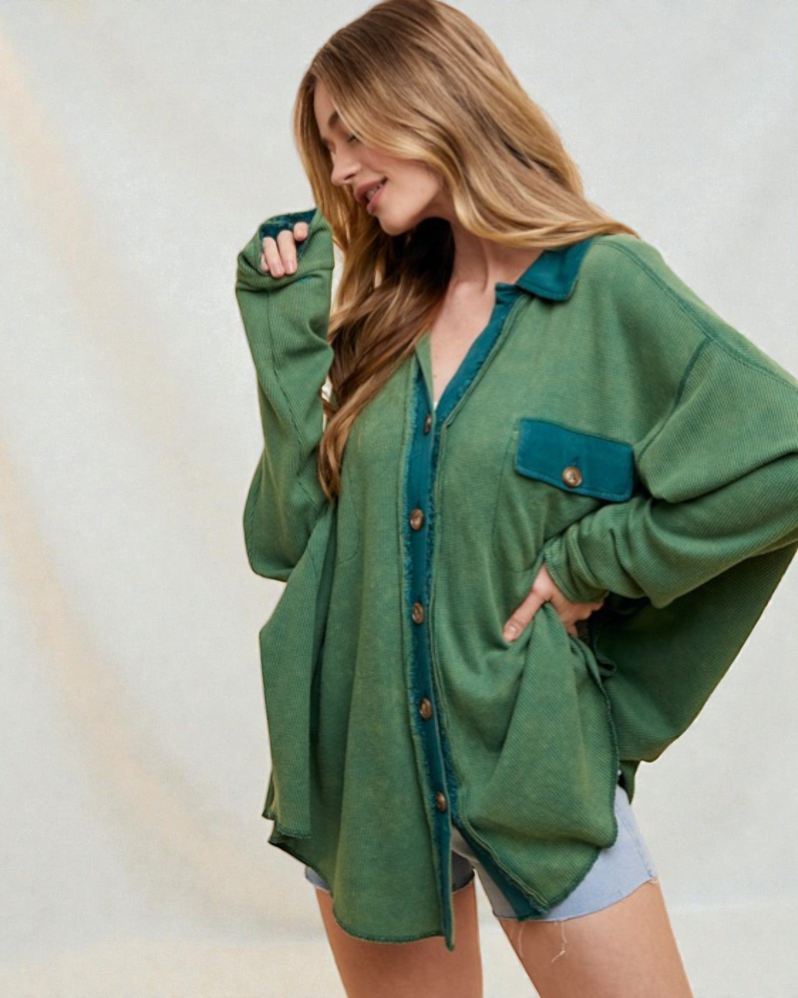 Woman wearing a green oversized shirt with a plain background