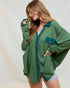 Woman wearing a green oversized shirt with a plain background