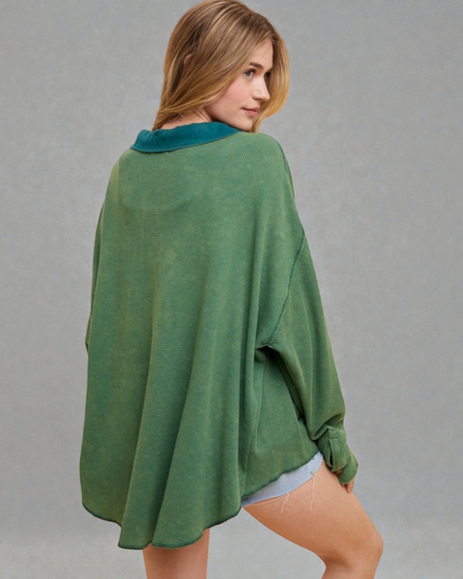 Woman wearing a green poncho against a gray background