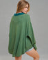 Woman wearing a green poncho against a gray background
