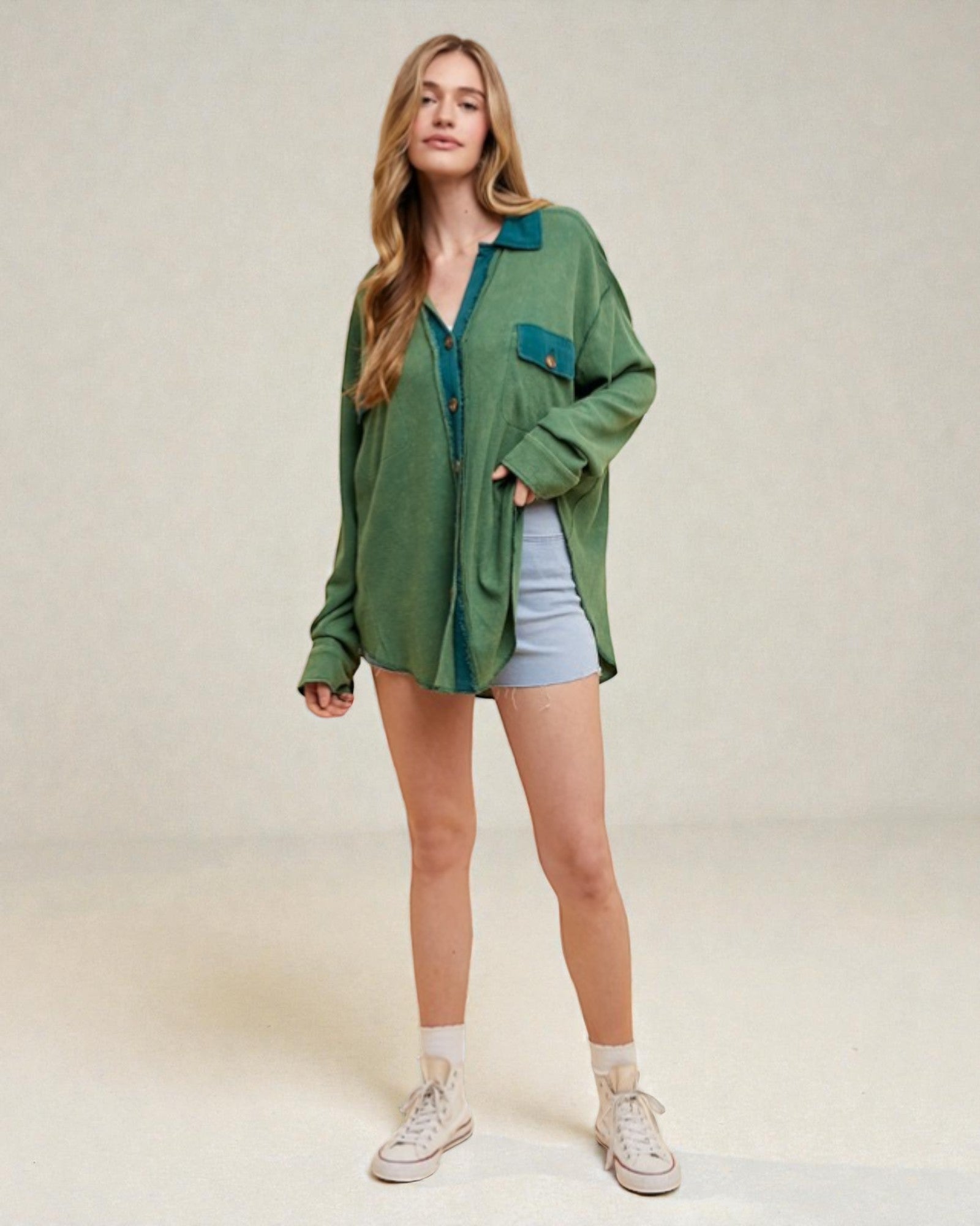 Woman wearing a green shirt and denim shorts on a plain background